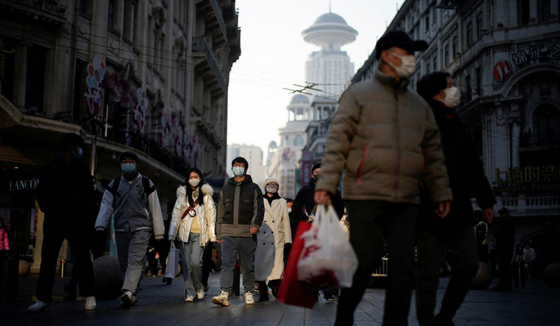 People wearing protective face masks walk on a street in China
